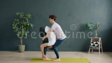 瑜伽老师和女学生在健身房做双人瑜伽，女生举重男生聊天